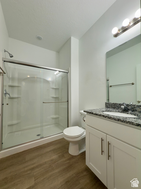 Full bath with a stall shower, wood finished floors, toilet, vanity, and a textured ceiling