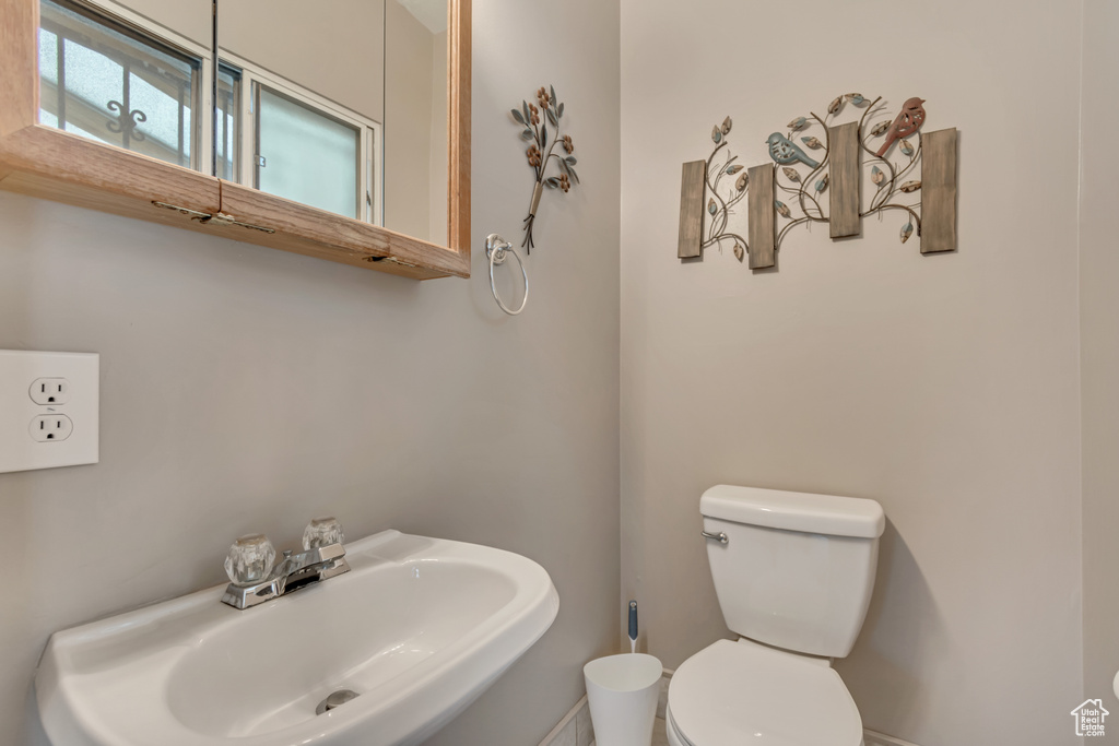Bathroom featuring a sink, toilet, and baseboards