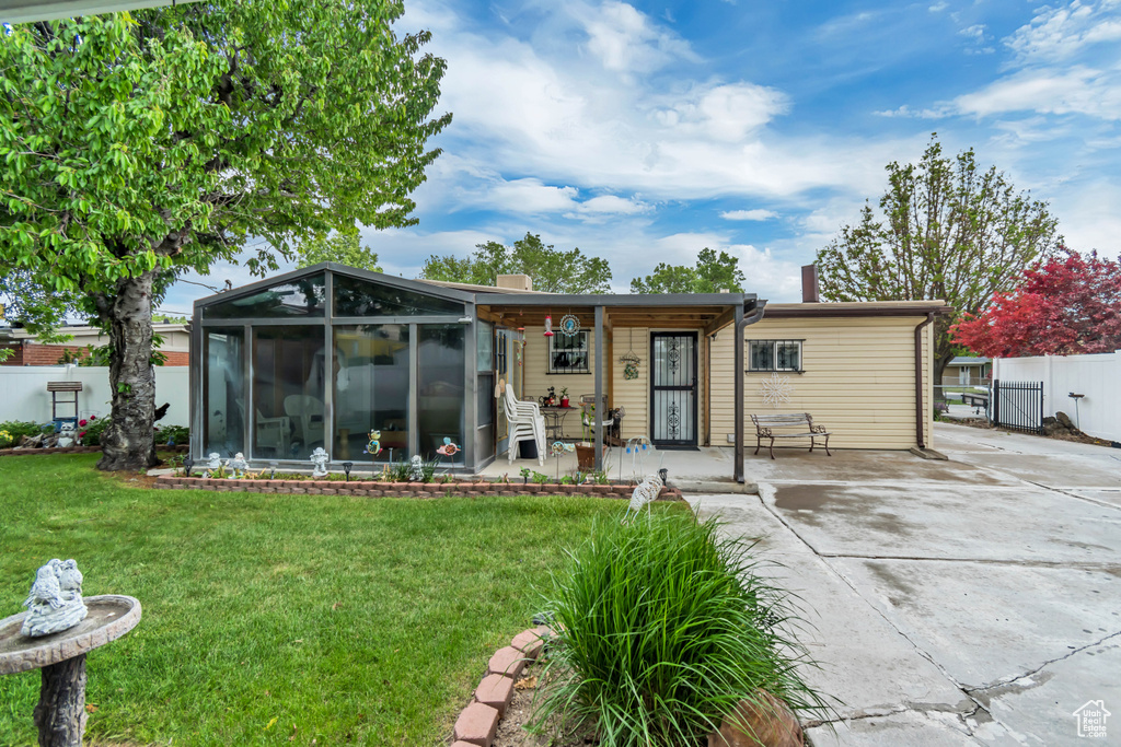 Back of property with a sunroom, concrete driveway, a chimney, and covered porch