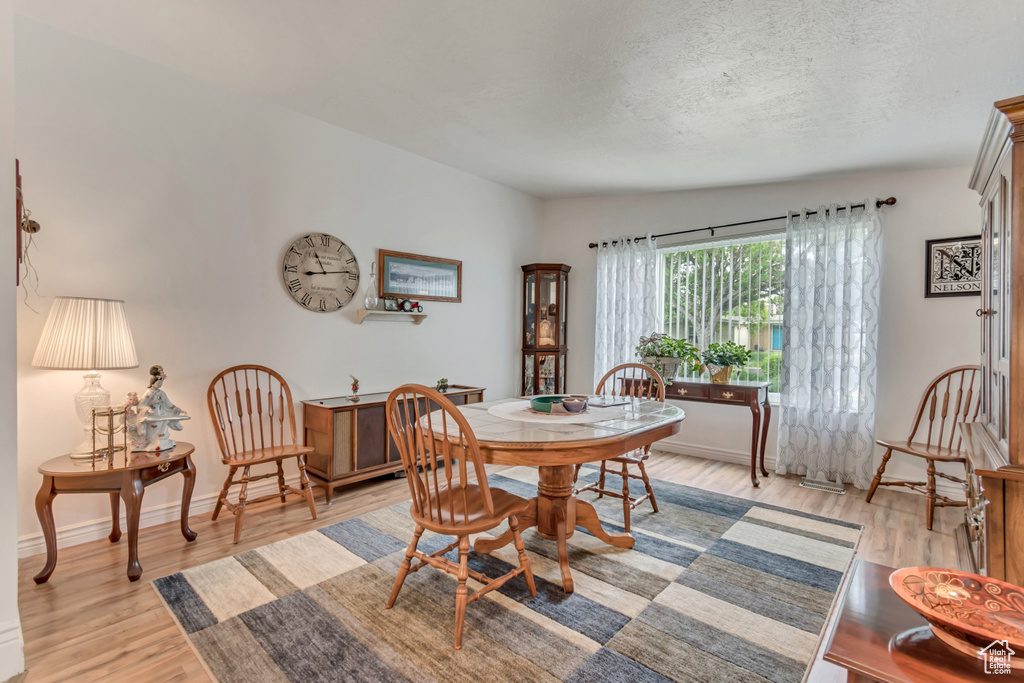 Dining space with light wood-type flooring, a textured ceiling, and baseboards
