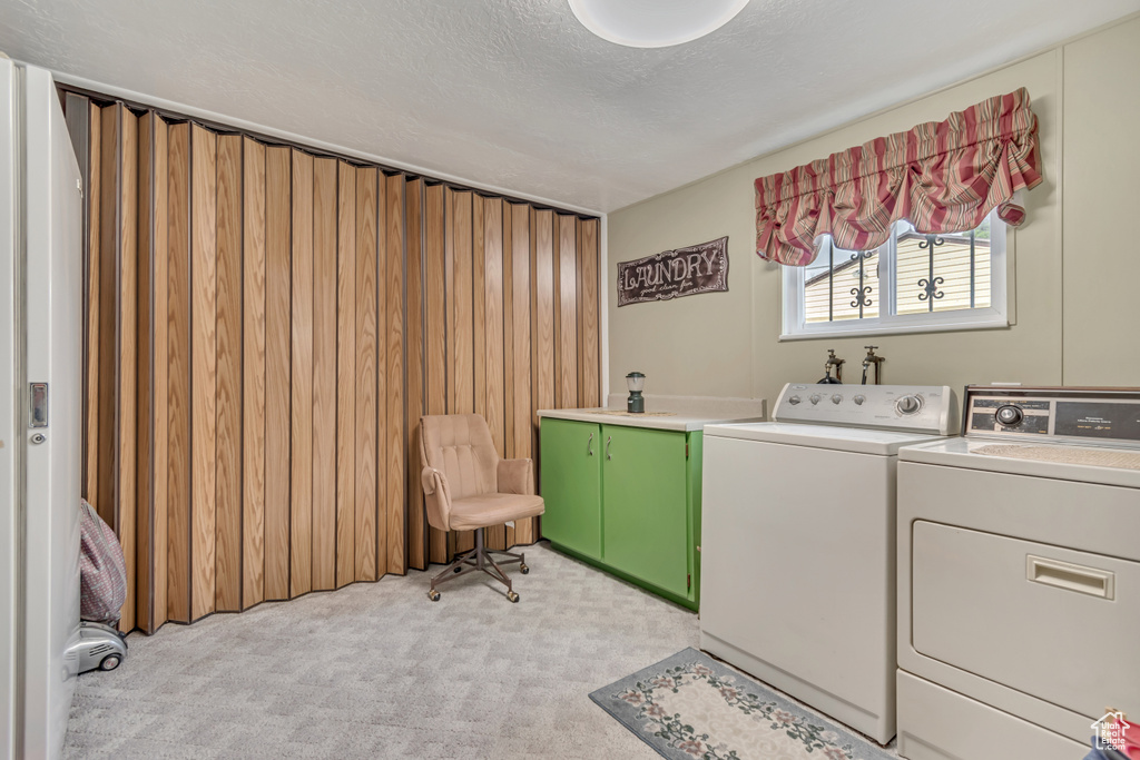 Washroom with separate washer and dryer, cabinet space, light colored carpet, and a textured ceiling