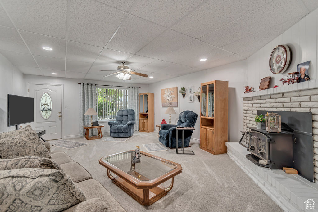 Living area featuring ceiling fan, light colored carpet, a wood stove, a paneled ceiling, and recessed lighting