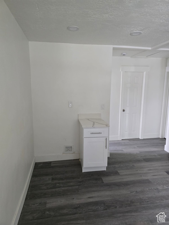 Spare room featuring baseboards, a textured ceiling, and dark wood-style flooring