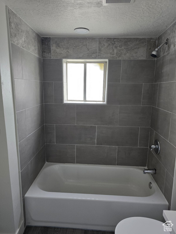Full bath featuring toilet, shower / bath combination, and a textured ceiling