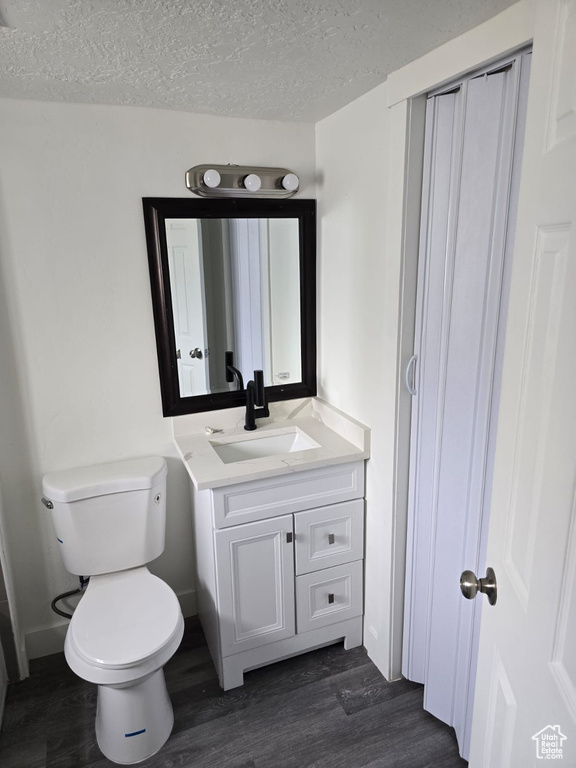 Bathroom with wood finished floors, toilet, a textured ceiling, and vanity