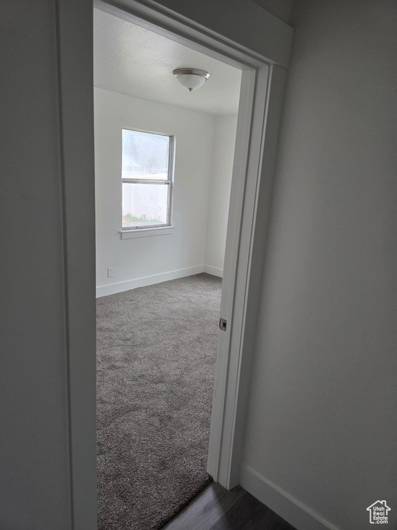 Spare room featuring baseboards and dark colored carpet