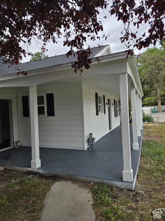 View of property exterior featuring a shingled roof and a porch