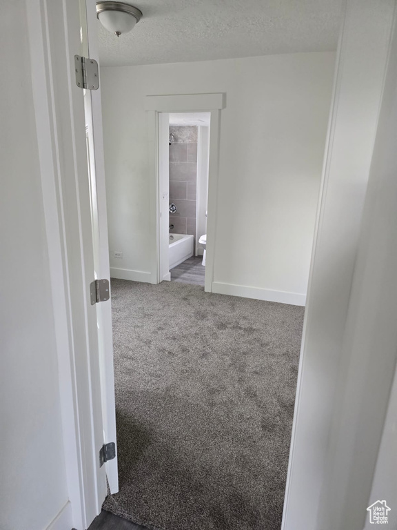 Spare room featuring baseboards, carpet flooring, and a textured ceiling