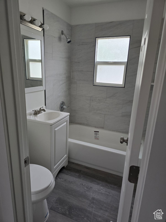Bathroom featuring plenty of natural light, vanity, toilet, and wood finished floors