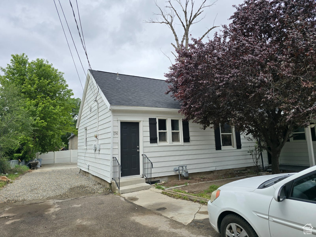 View of front facade featuring roof with shingles and fence