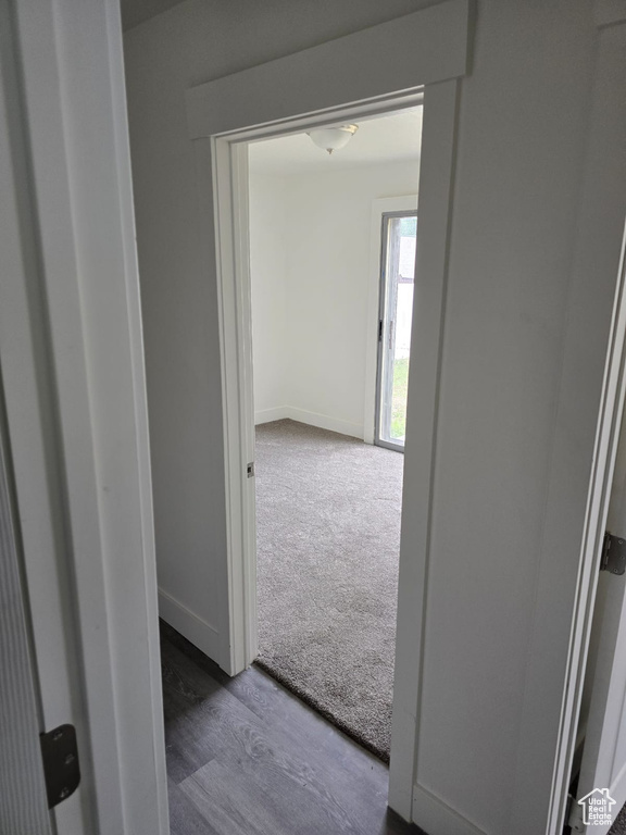 Hallway with baseboards, carpet flooring, and wood finished floors
