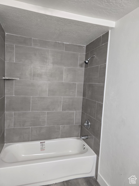 Full bath featuring shower / tub combination, a textured ceiling, and wood finished floors