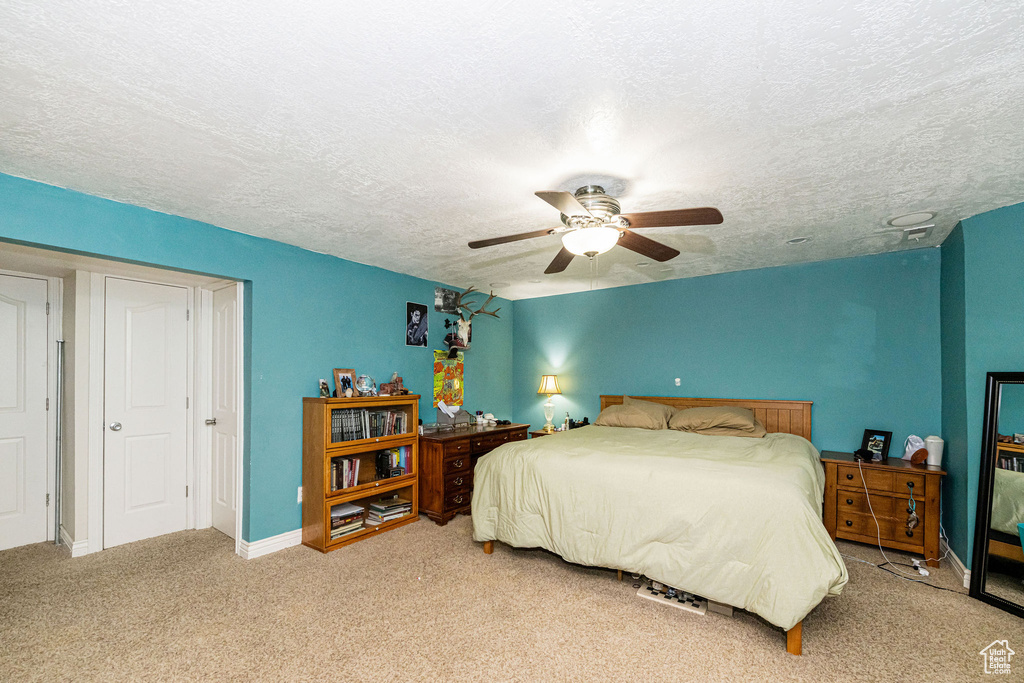 Carpeted bedroom with a textured ceiling, a ceiling fan, and baseboards