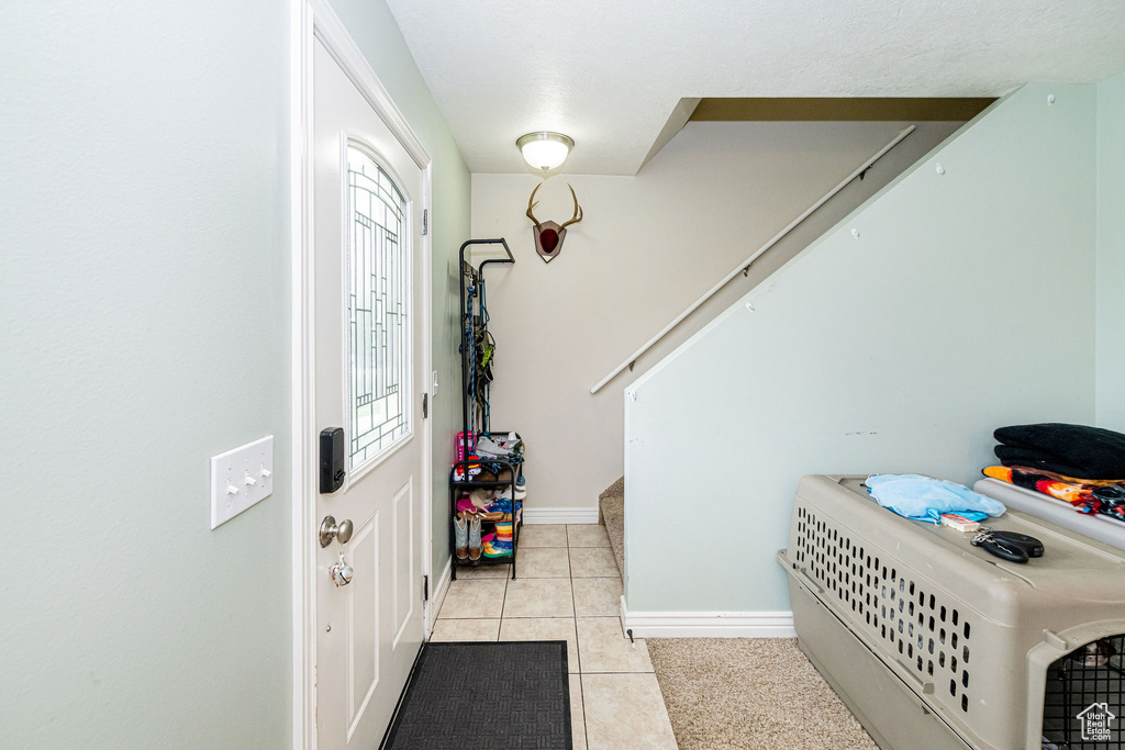Foyer featuring stairway, light tile patterned floors, and baseboards