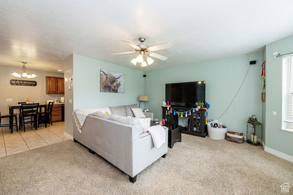 Living room featuring light carpet, a chandelier, a ceiling fan, baseboards, and light tile patterned floors