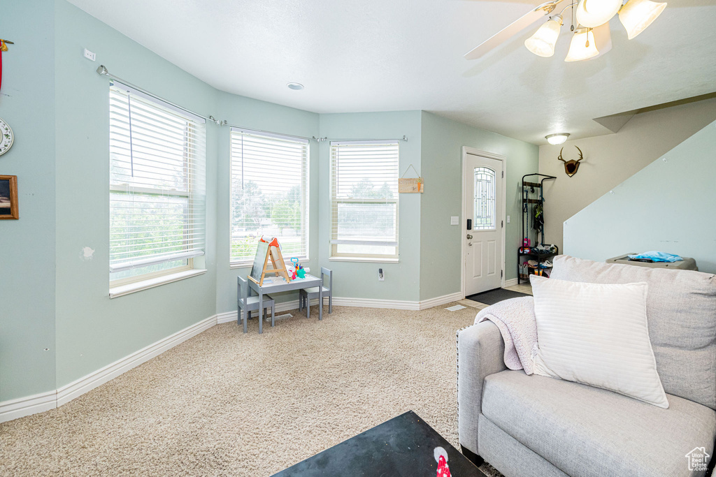 Carpeted living room with plenty of natural light, baseboards, and a ceiling fan