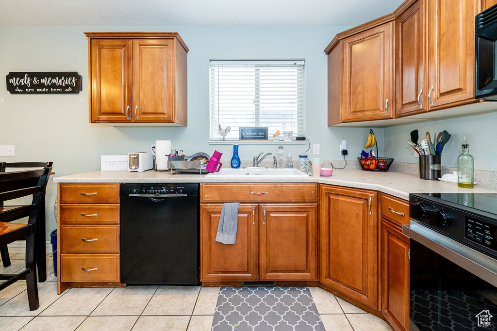 Kitchen with black appliances, a sink, brown cabinets, and light countertops