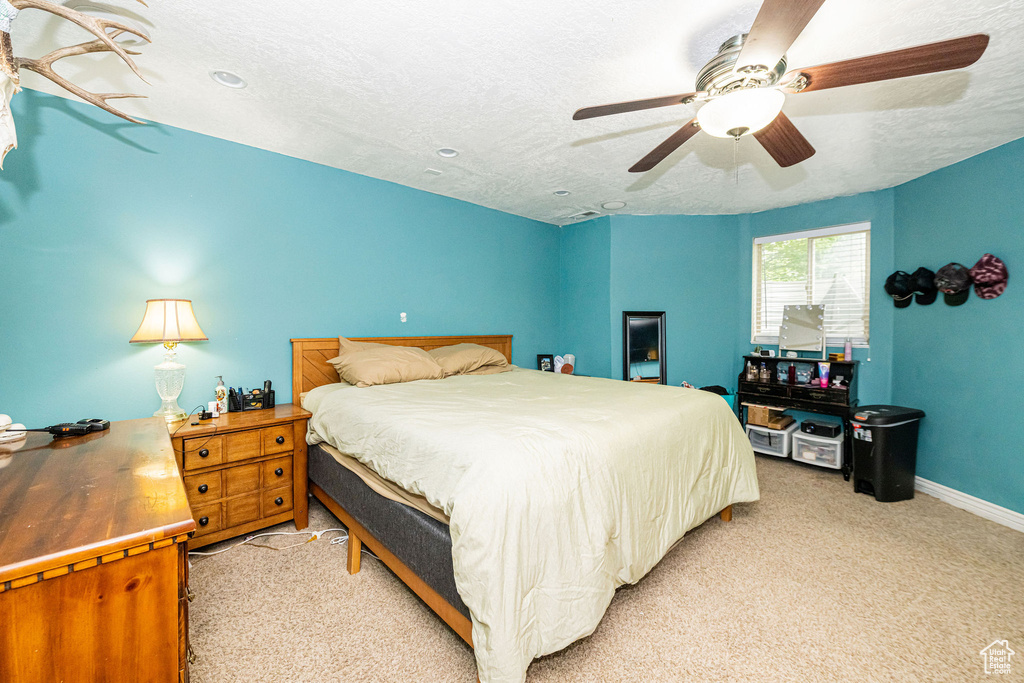 Bedroom with light carpet, baseboards, ceiling fan, and a textured ceiling
