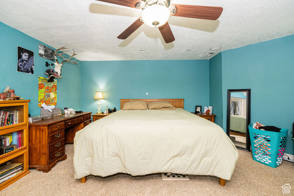 Bedroom featuring light carpet, a textured ceiling, and a ceiling fan