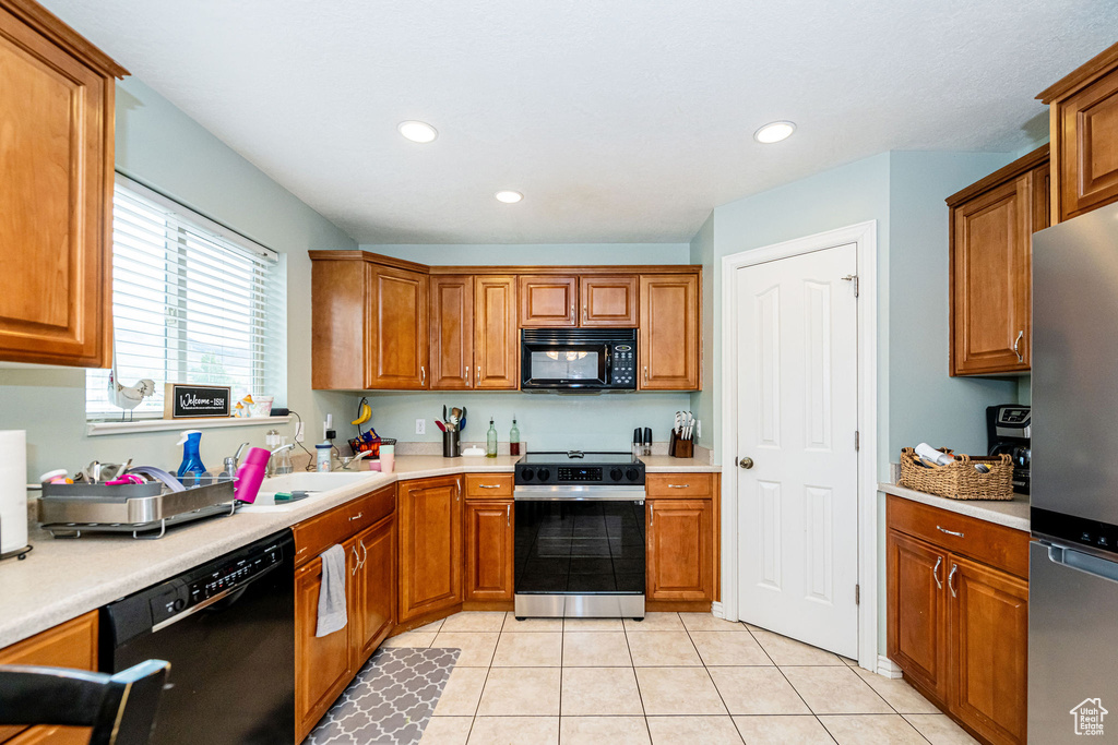 Kitchen featuring black appliances, brown cabinets, light tile patterned flooring, recessed lighting, and light countertops
