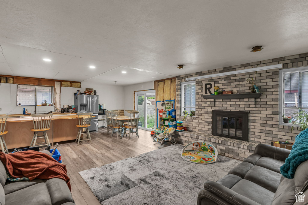 Living area with light wood-style floors, a brick fireplace, and recessed lighting