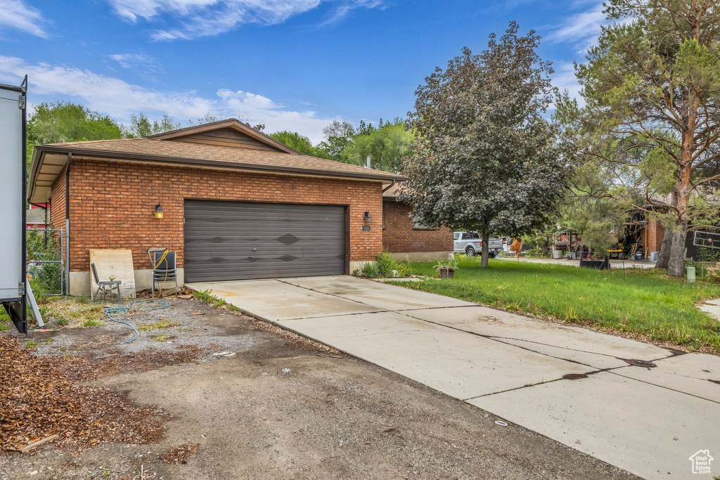 View of home's exterior with brick siding, driveway, a garage, and a yard