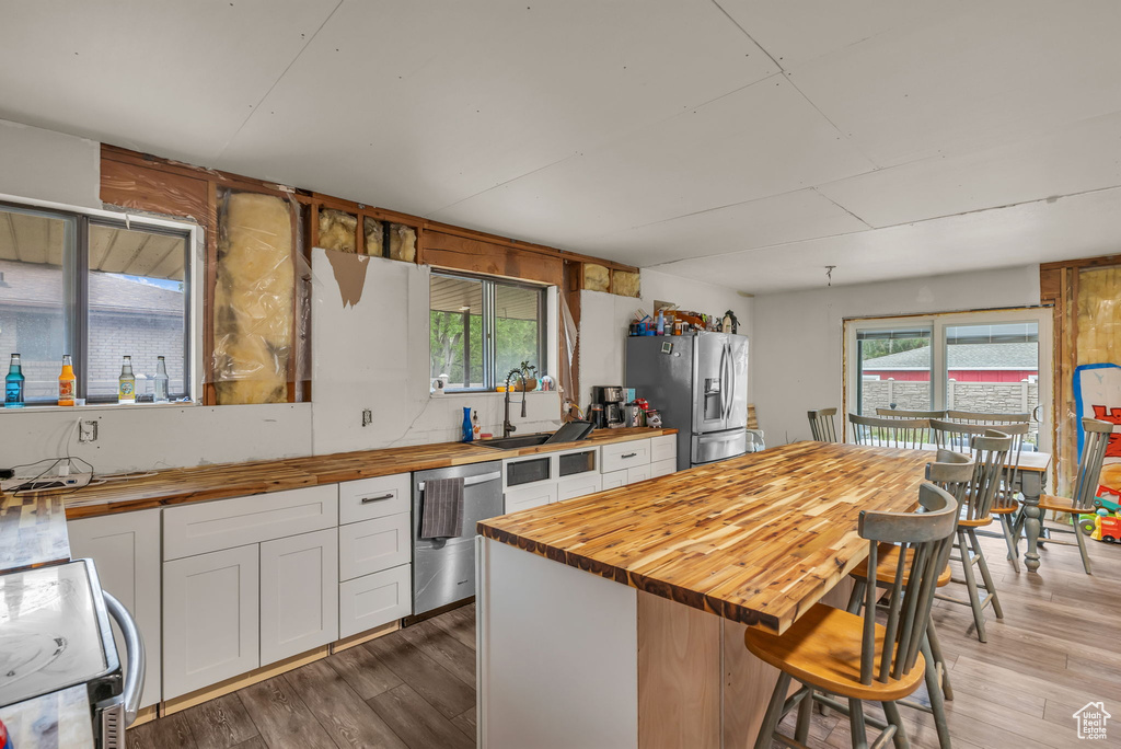 Kitchen with wooden counters, appliances with stainless steel finishes, light wood-type flooring, and white cabinets