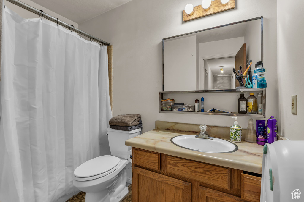 Full bathroom featuring toilet, vanity, and curtained shower