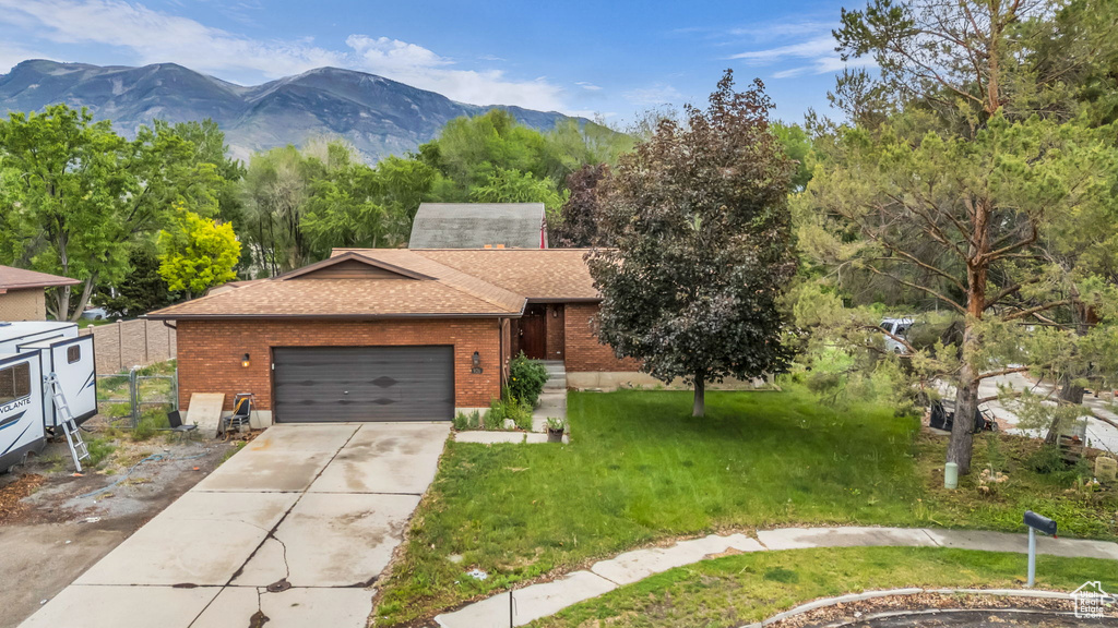View of front of house featuring brick siding, concrete driveway, a mountain view, and an attached garage
