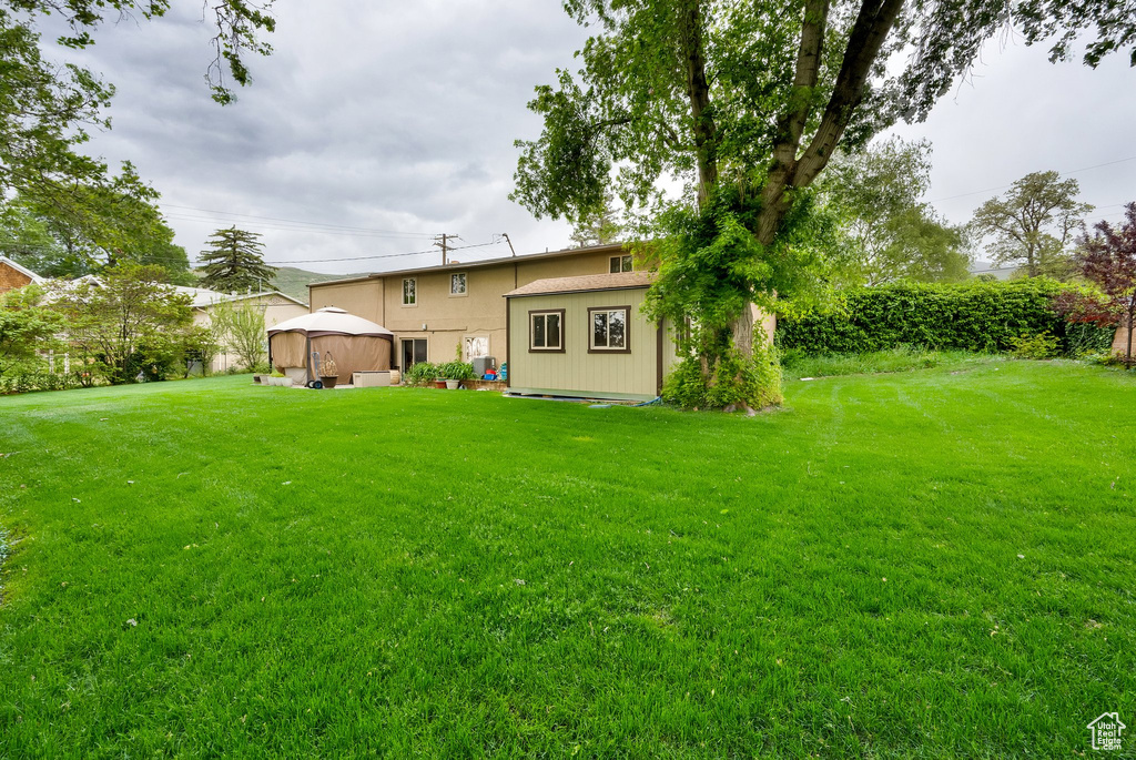 View of grassy yard with an outdoor structure and a gazebo