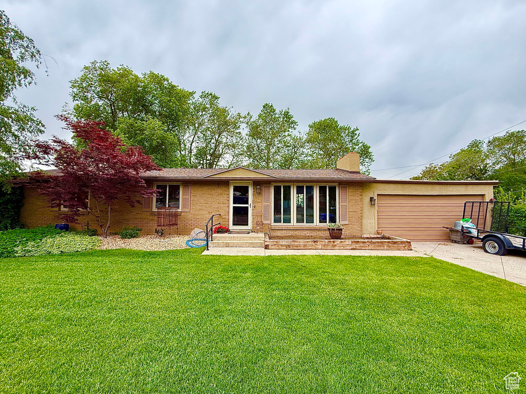 Rear view of house featuring brick siding, a yard, a garage, and concrete driveway