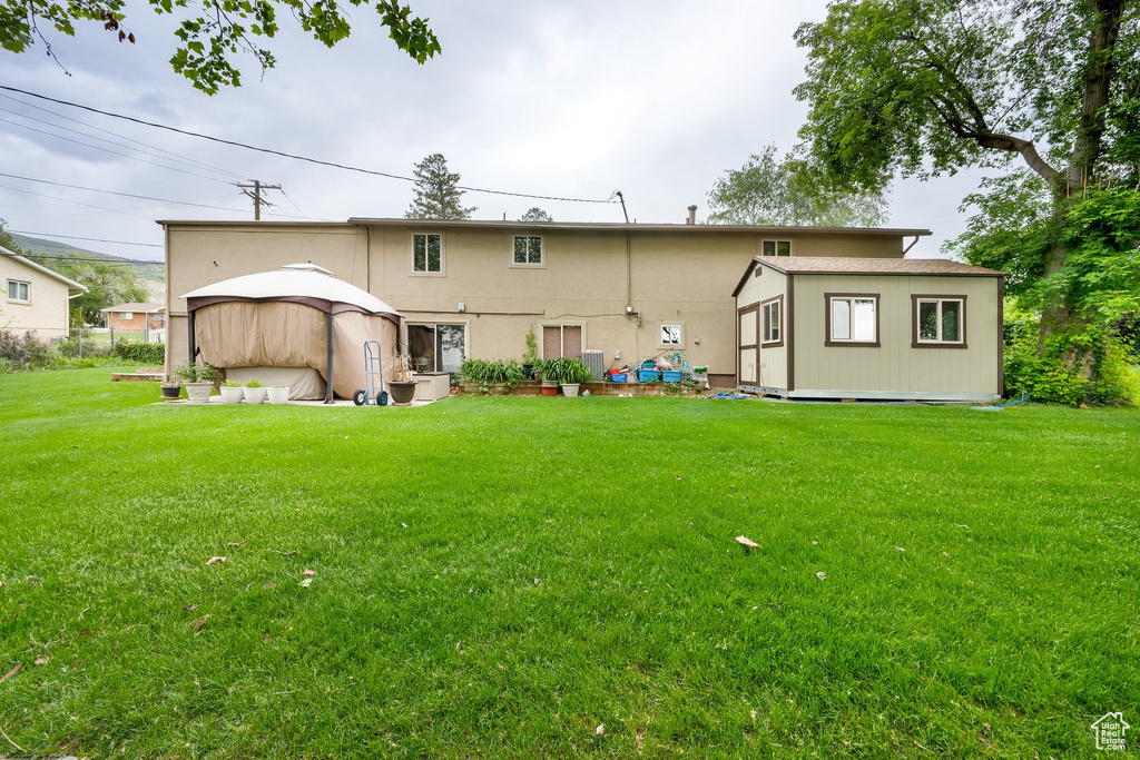 Back of property with a lawn and an outdoor structure