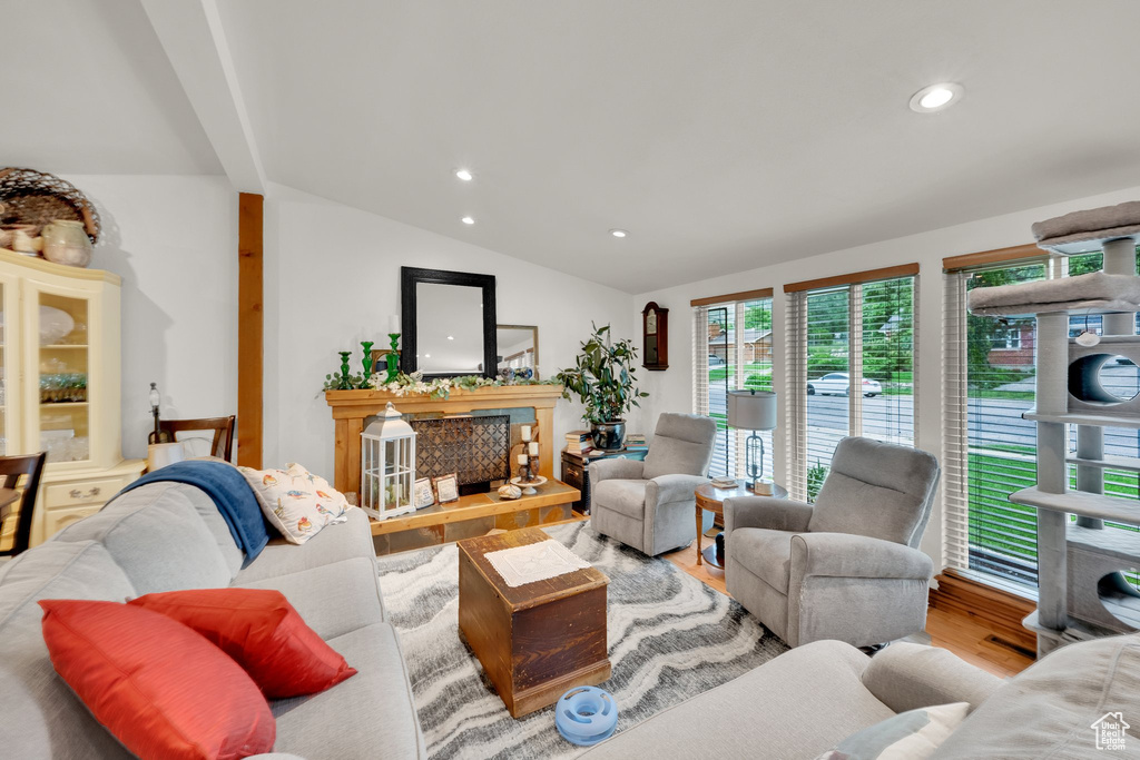 Living area featuring vaulted ceiling, wood finished floors, recessed lighting, and a fireplace with raised hearth