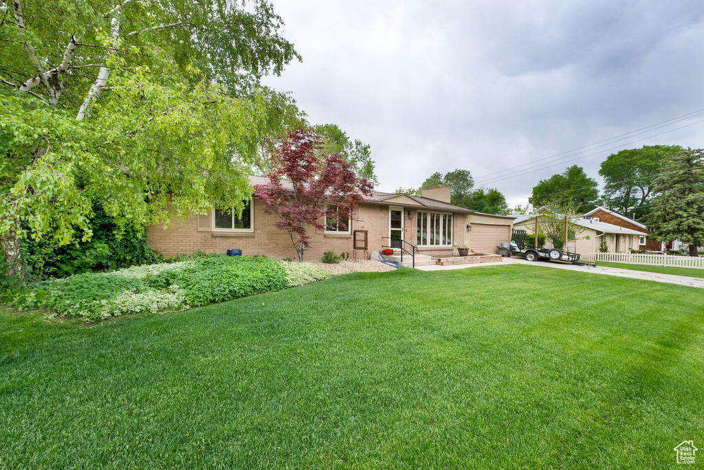 View of front of home featuring brick siding, a chimney, and concrete driveway