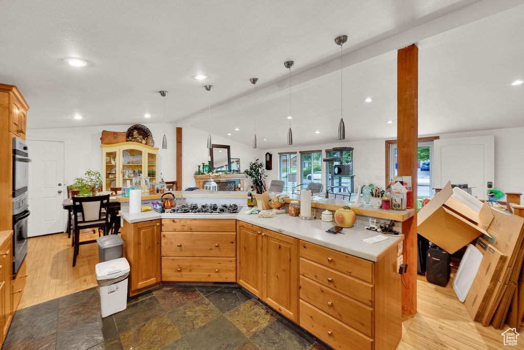 Kitchen featuring stainless steel gas cooktop, light countertops, recessed lighting, decorative light fixtures, and dark stone finish flooring