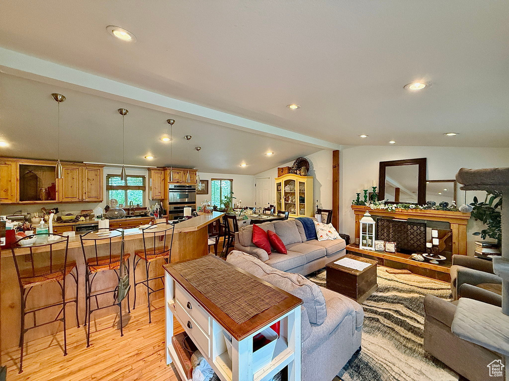 Living room with light wood finished floors, lofted ceiling, recessed lighting, and a fireplace