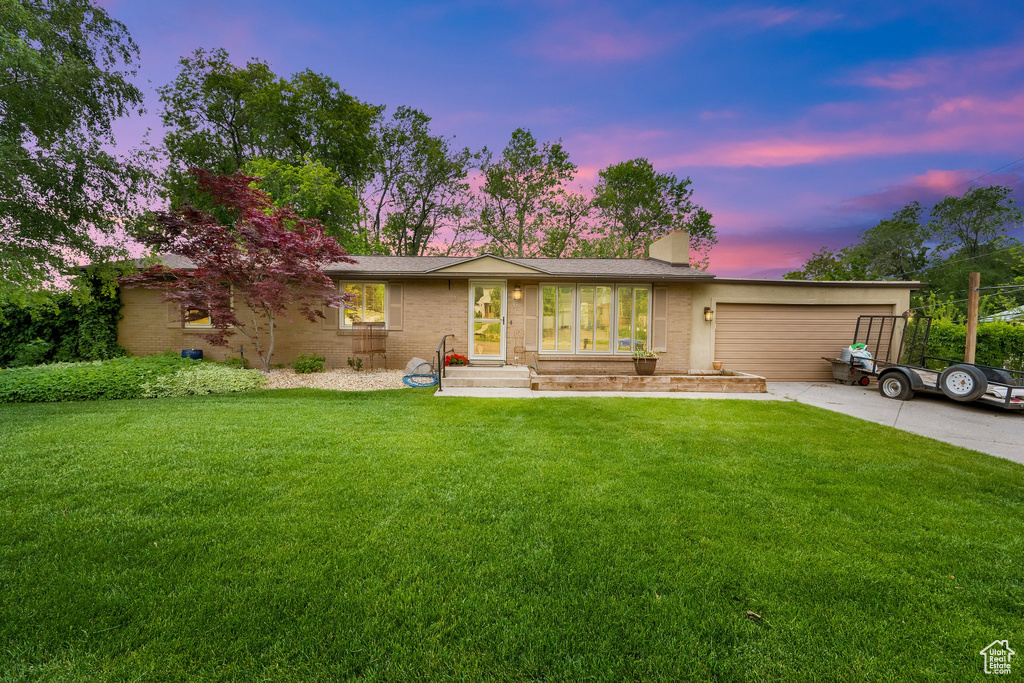 Ranch-style house with driveway, a front lawn, and an attached garage