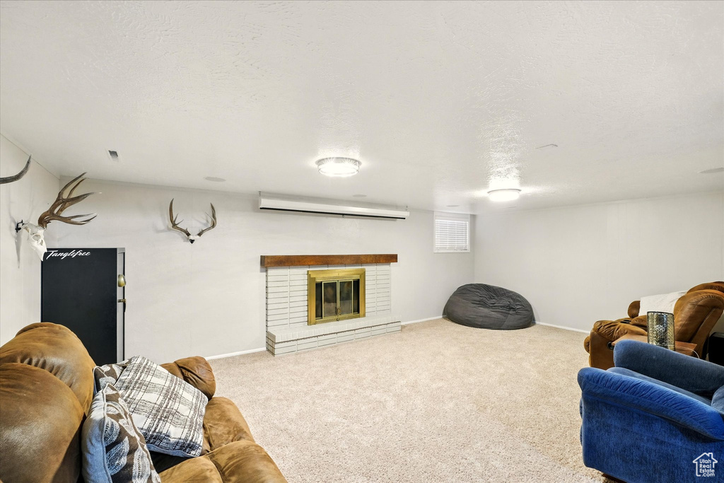Living room featuring carpet flooring, a wall mounted air conditioner, baseboards, and a fireplace