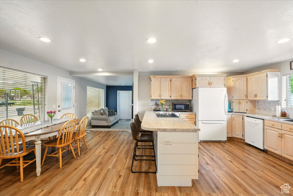 Kitchen featuring white appliances, light brown cabinets, backsplash, recessed lighting, and light wood finished floors