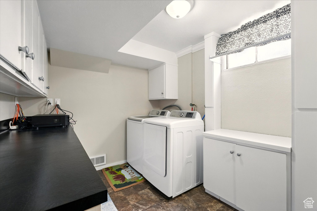 Washroom with separate washer and dryer, cabinet space, dark stone finish flooring, and baseboards