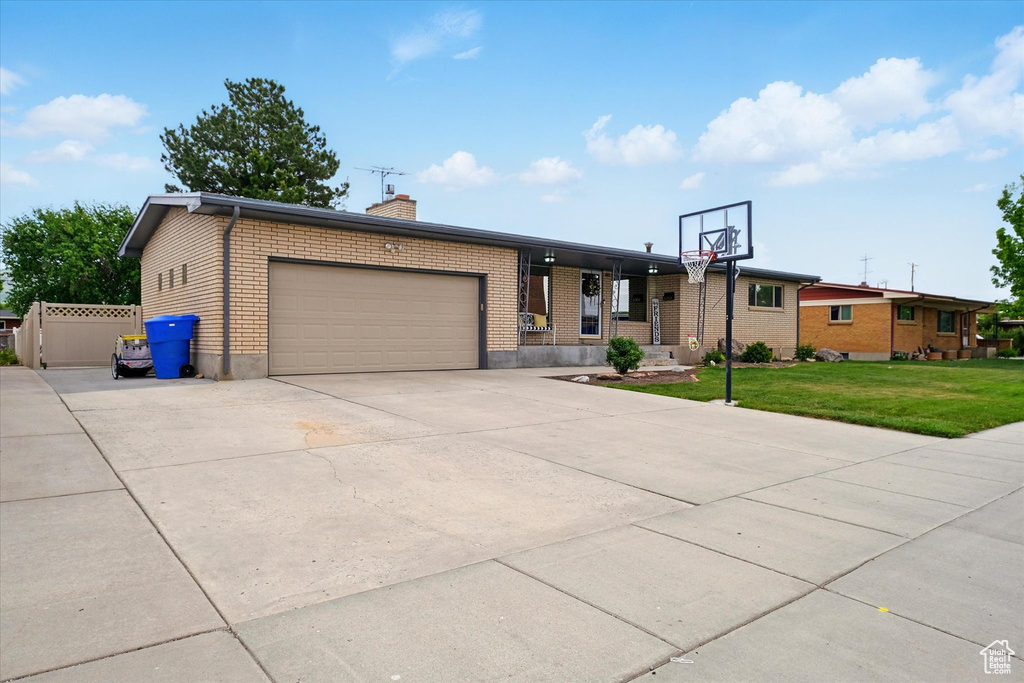 View of front of house with an attached garage, a chimney, a front yard, concrete driveway, and brick siding