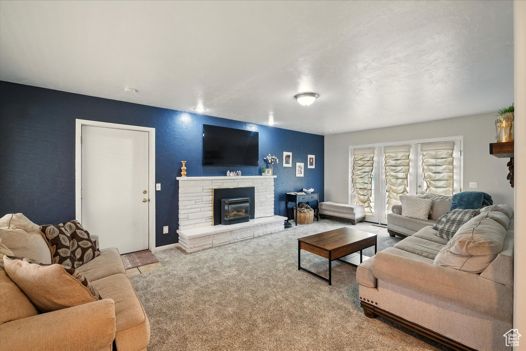 Living room with carpet, a stone fireplace, and baseboards