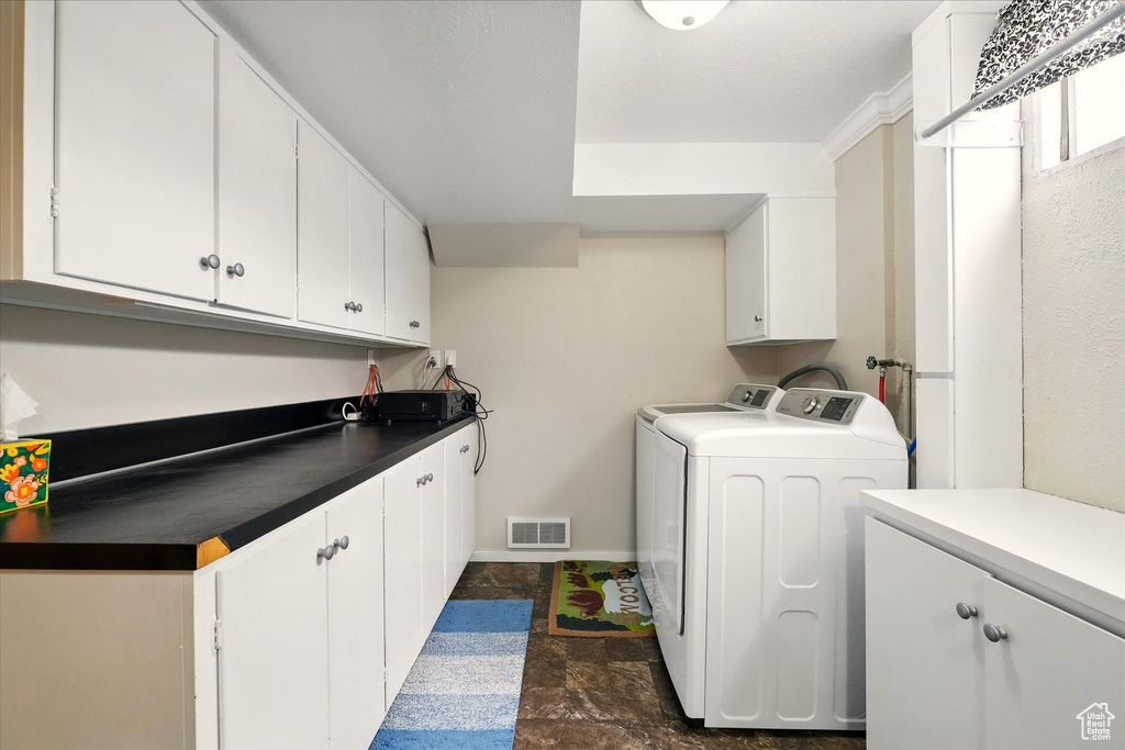 Clothes washing area featuring cabinet space, washer and clothes dryer, dark stone finish flooring, and baseboards