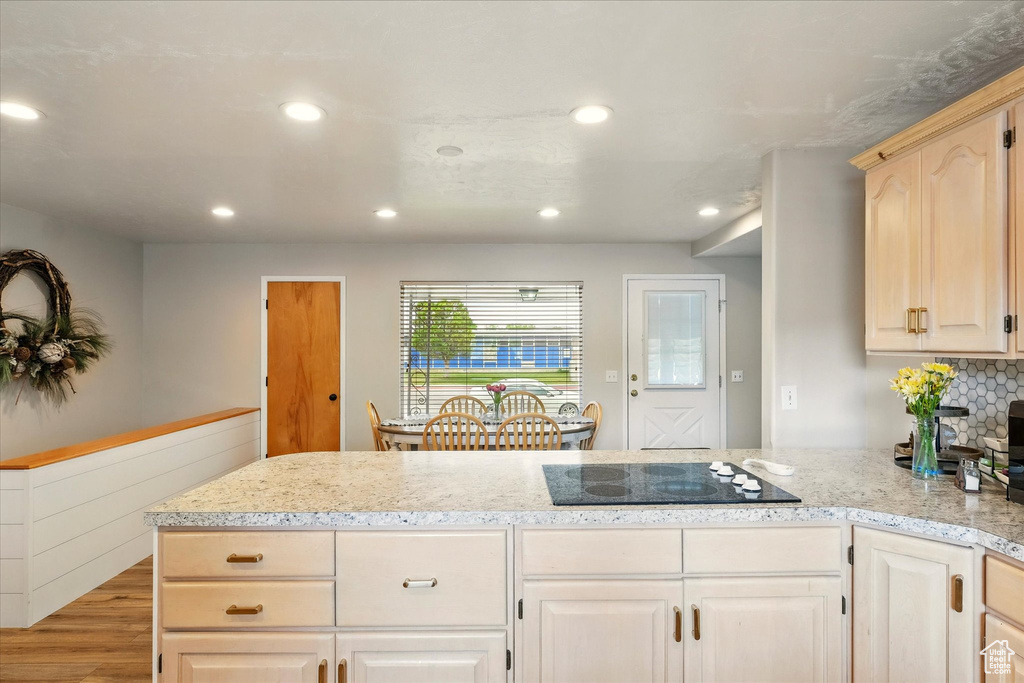 Kitchen with black electric cooktop, recessed lighting, light wood-style floors, a peninsula, and light stone counters