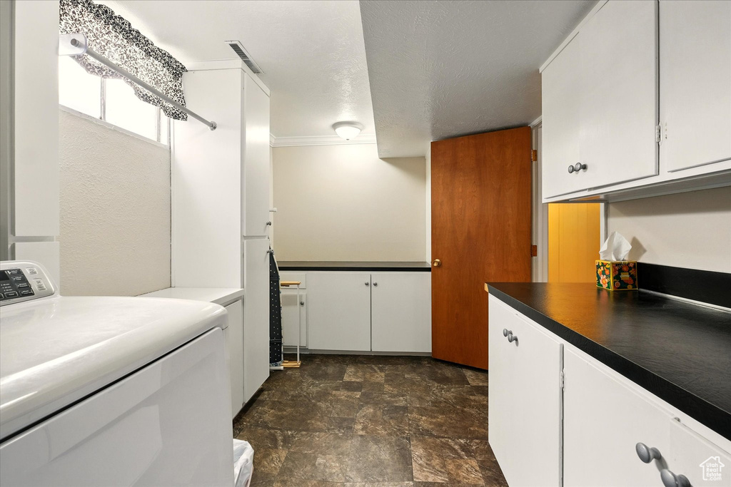 Clothes washing area featuring washer / clothes dryer, cabinet space, and stone finish flooring