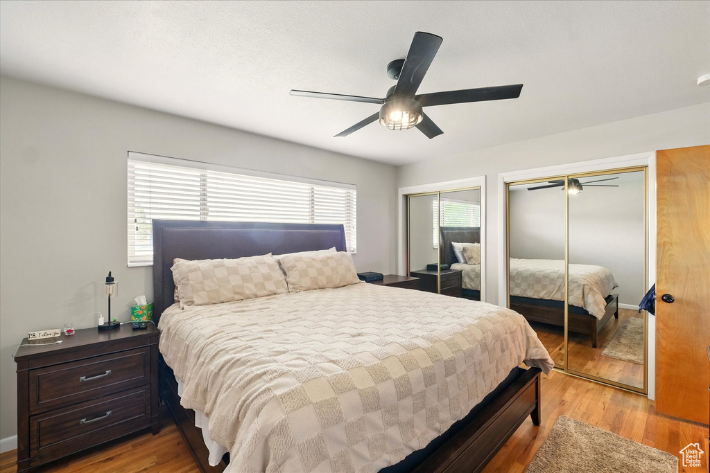 Bedroom with two closets, light wood-type flooring, and a ceiling fan
