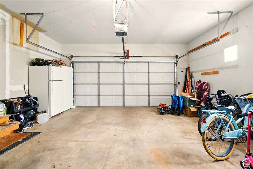 Garage with freestanding refrigerator and a garage door opener