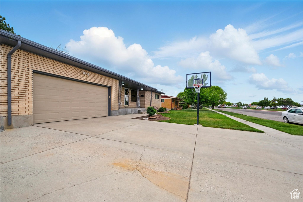 View of front facade featuring brick siding, concrete driveway, an attached garage, and a front lawn