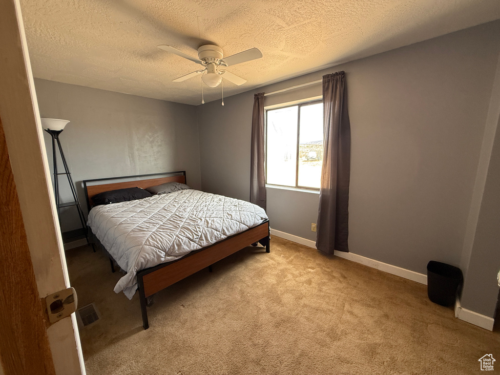 Carpeted bedroom with a textured ceiling, a ceiling fan, and baseboards