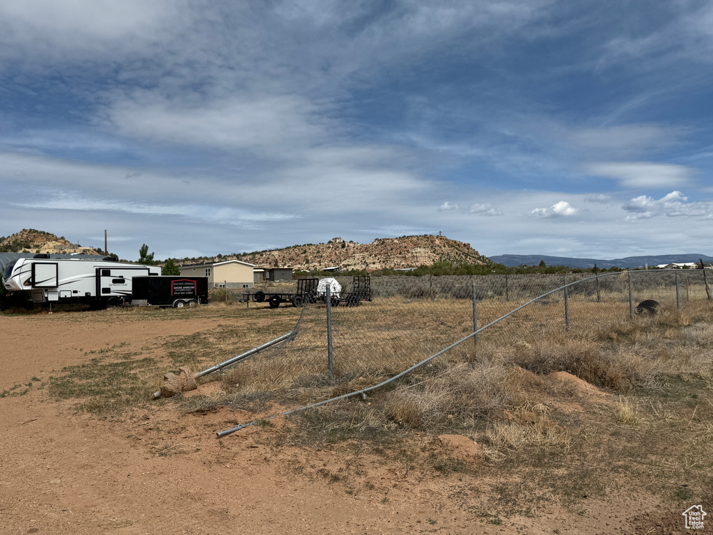 View of yard with fence, a rural view, and a mountain view
